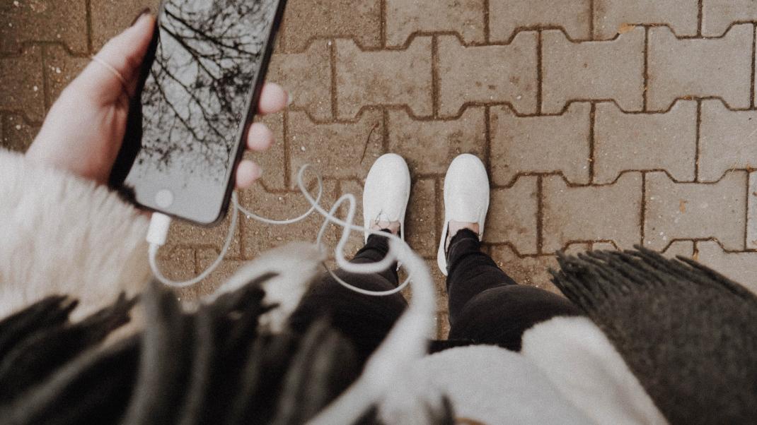 Γυναίκα με λευκά sneakers και κινητό στον δρόμο