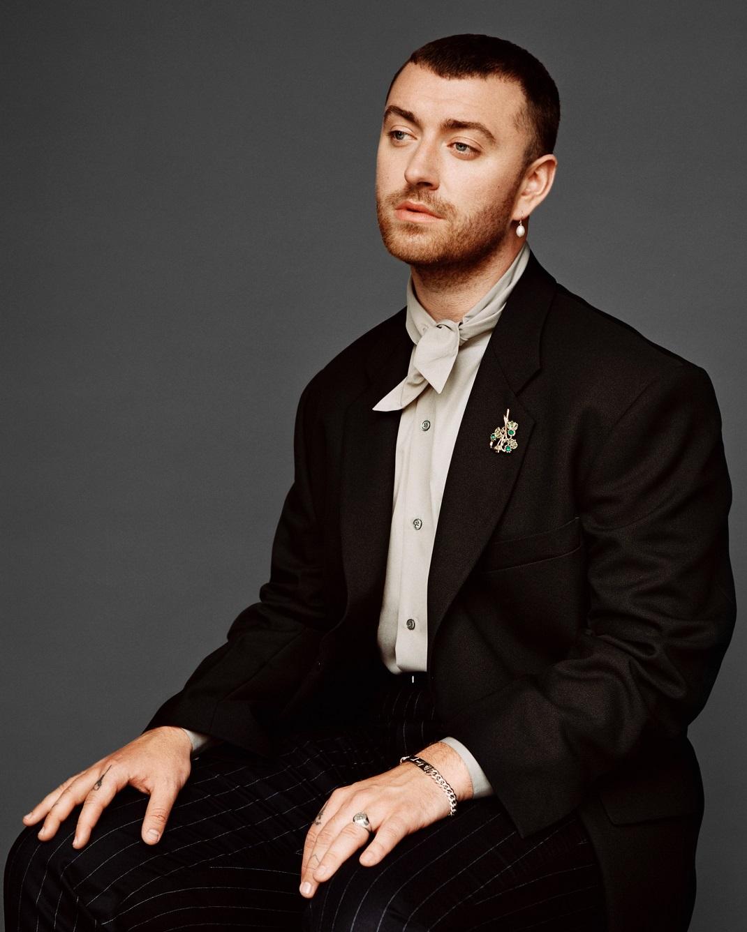 Sam Smith photographed by Alasdair McLellan, Hertfordshire, June 16, 2020. Stylist Ben Reardon. Styling Assistant Niccolo Torelli. Hair Anthony Turner. Make-up Anne Sofie Costa. Photography assistance Lex Kembery and Simon Mackinlay. Sam wears cotton poplin tie-neck shirt by Hermes. Black wool oversized blazer and navy wool pinstripe trousers by Random Identities. Pearl drop earring vintage. Gold and emerald brooch vintage. Silver signet ring and ‘Love Goes’ identity bracelet engraved with Sam Smith’s handwriting by Bunney.